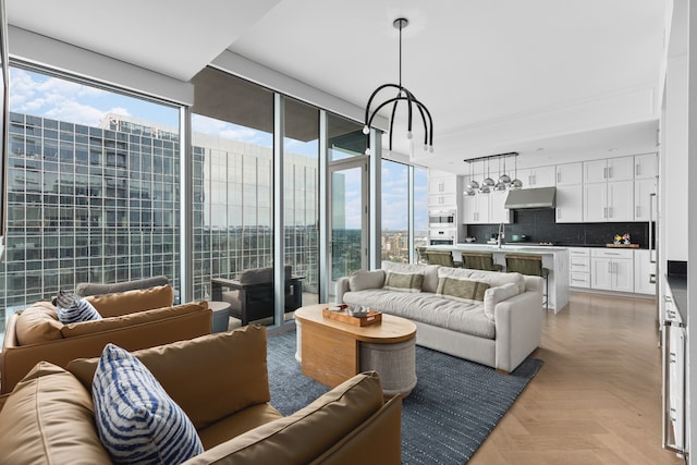 living room featuring plenty of natural light, sink, light parquet floors, and a chandelier