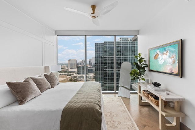 bedroom with ceiling fan, a wall of windows, access to outside, and light parquet flooring