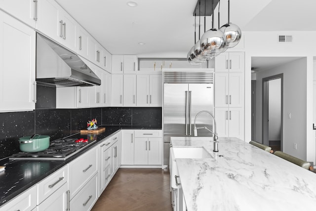 kitchen featuring decorative backsplash, white cabinets, hanging light fixtures, and dark stone countertops