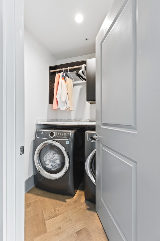 clothes washing area featuring washer and clothes dryer and light parquet flooring