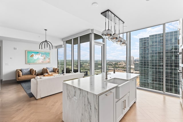 kitchen with expansive windows, white cabinetry, hanging light fixtures, and light parquet flooring