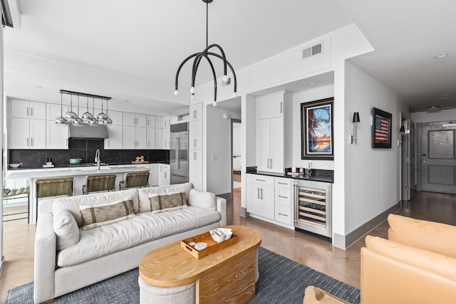 living room featuring light hardwood / wood-style flooring, wine cooler, and sink