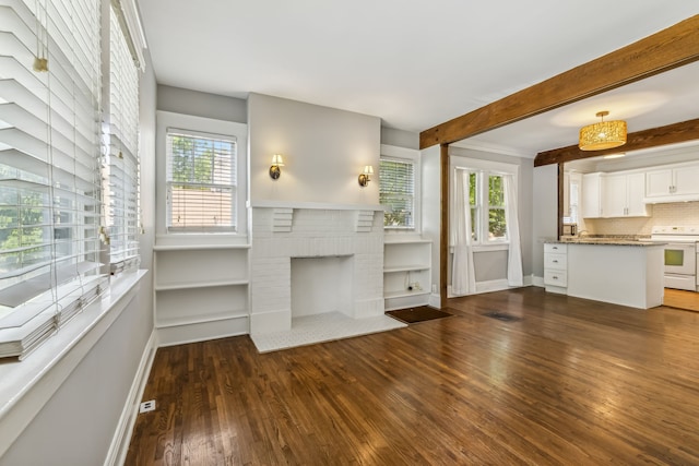 unfurnished living room with dark wood-type flooring, beam ceiling, plenty of natural light, and a brick fireplace