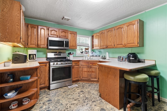 kitchen with a kitchen breakfast bar, a textured ceiling, stainless steel appliances, and kitchen peninsula