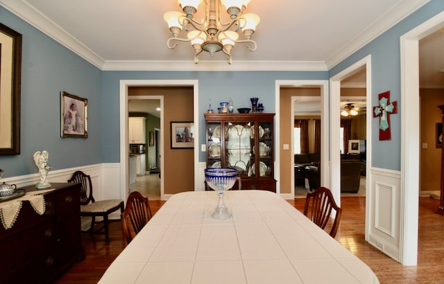 dining area with ceiling fan with notable chandelier, ornamental molding, and hardwood / wood-style flooring