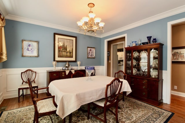 dining space with crown molding, dark wood-type flooring, and an inviting chandelier