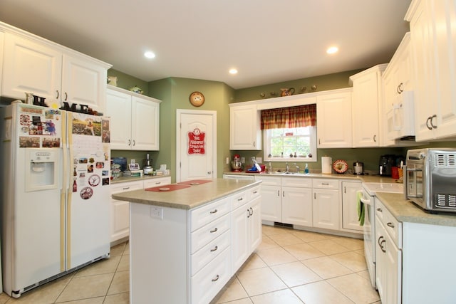 kitchen with white appliances, a kitchen island, and white cabinets