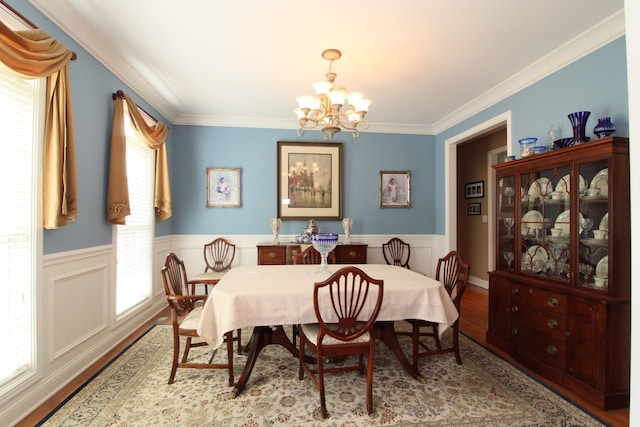 dining room featuring light wood-type flooring, ornamental molding, and an inviting chandelier