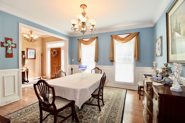 dining area with light hardwood / wood-style floors, a chandelier, and ornamental molding