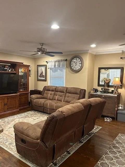 living room with crown molding, dark wood-type flooring, and ceiling fan