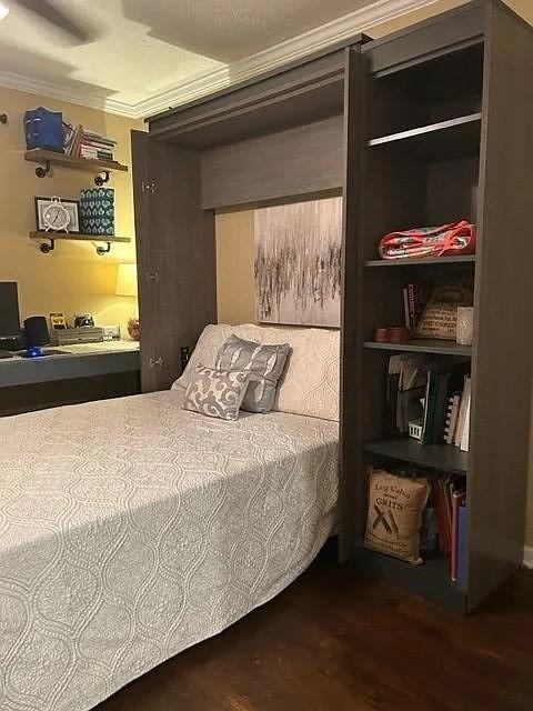 bedroom with ornamental molding and dark hardwood / wood-style floors