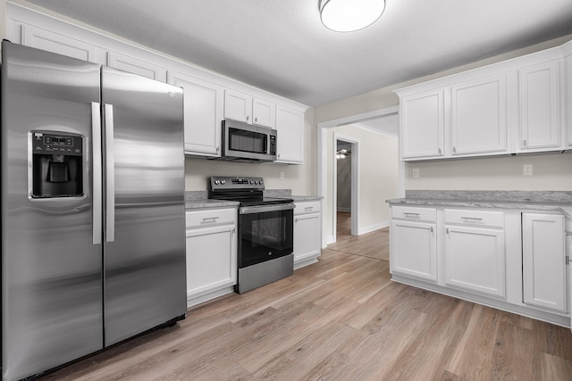 kitchen featuring light wood-type flooring, stainless steel appliances, and white cabinetry