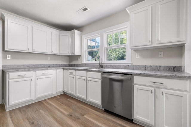 kitchen featuring light stone counters, white cabinets, stainless steel dishwasher, light wood-type flooring, and sink