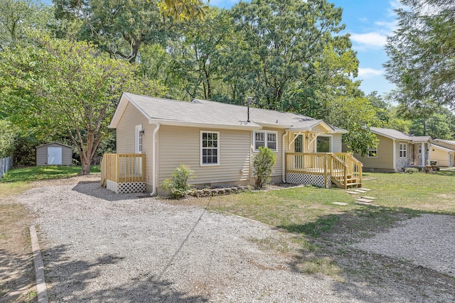 single story home with a front yard, a storage shed, and a wooden deck