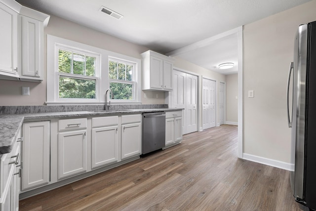 kitchen featuring appliances with stainless steel finishes, dark hardwood / wood-style floors, sink, and white cabinetry