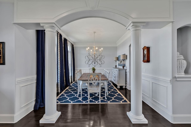 dining room featuring a notable chandelier, dark wood-type flooring, ornamental molding, and decorative columns