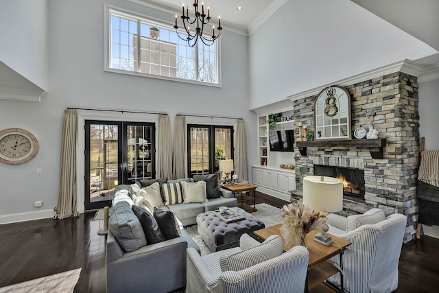 living room with a stone fireplace, dark hardwood / wood-style floors, french doors, an inviting chandelier, and a towering ceiling