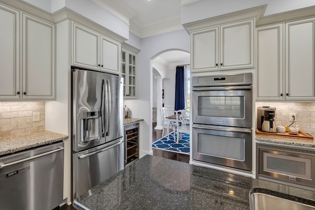 kitchen featuring decorative backsplash, dark stone counters, stainless steel appliances, and hardwood / wood-style floors