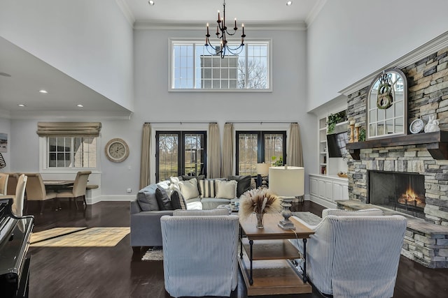 living room featuring a fireplace, dark hardwood / wood-style flooring, french doors, crown molding, and a notable chandelier