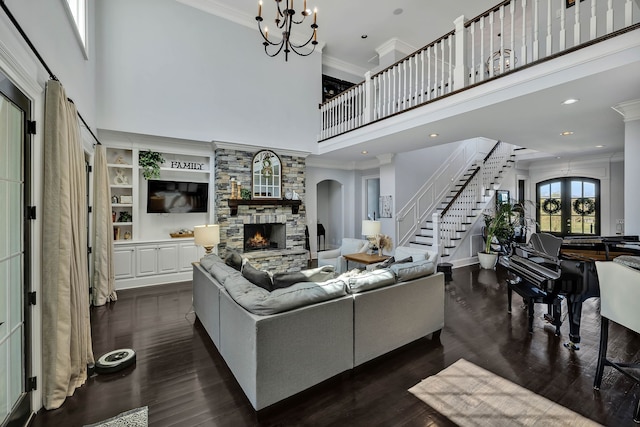 living room featuring a stone fireplace, dark hardwood / wood-style floors, crown molding, and a chandelier