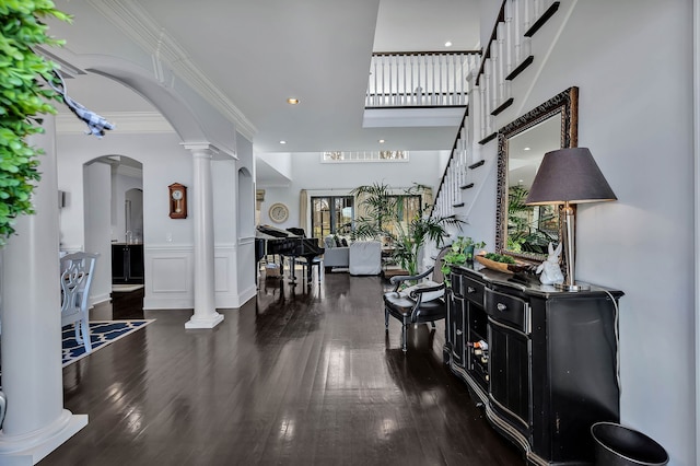 foyer with decorative columns, dark wood-type flooring, and a high ceiling