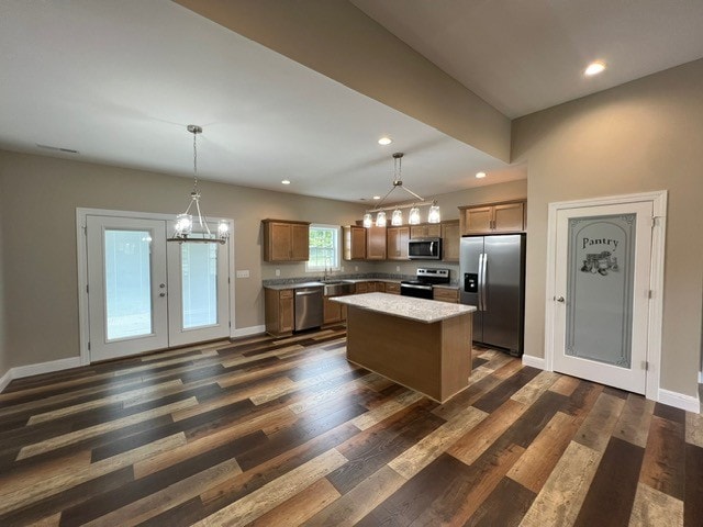 kitchen with appliances with stainless steel finishes, dark wood-type flooring, a center island, and hanging light fixtures