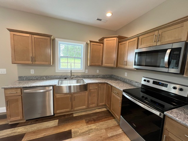 kitchen with sink, stainless steel appliances, and light hardwood / wood-style floors