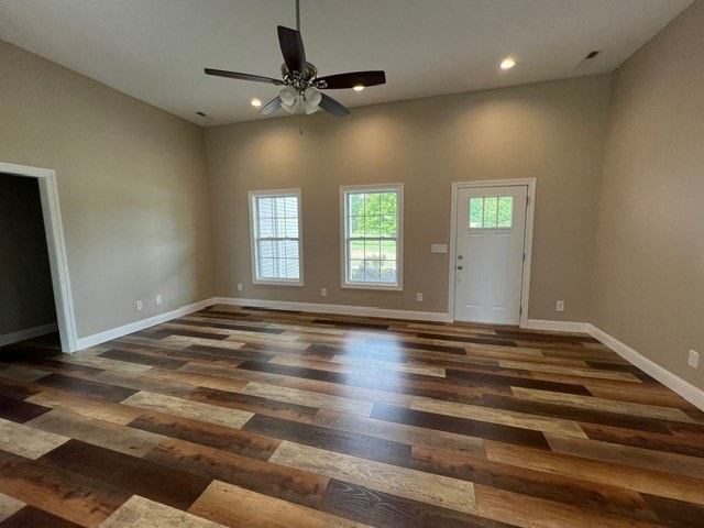 interior space featuring ceiling fan, dark hardwood / wood-style floors, and a high ceiling