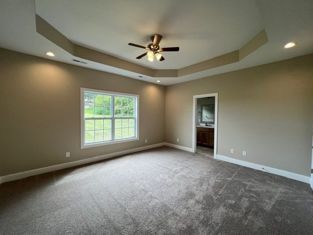 carpeted empty room with ceiling fan and a tray ceiling