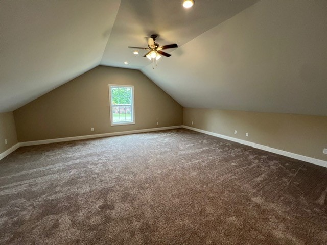 additional living space with lofted ceiling, dark carpet, and ceiling fan