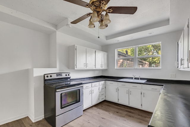 kitchen with a tray ceiling, white cabinetry, light hardwood / wood-style floors, and stainless steel electric range oven