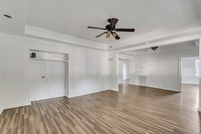 empty room featuring ceiling fan, a tray ceiling, and hardwood / wood-style flooring