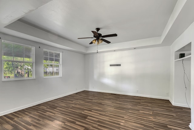 spare room with wood-type flooring, a tray ceiling, and ceiling fan