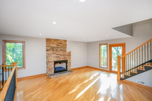 unfurnished living room with a stone fireplace and light hardwood / wood-style floors