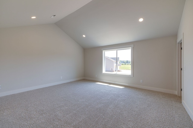 spare room featuring carpet and lofted ceiling