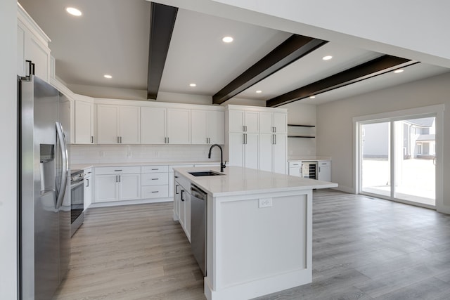 kitchen featuring light hardwood / wood-style flooring, a center island with sink, backsplash, stainless steel appliances, and sink