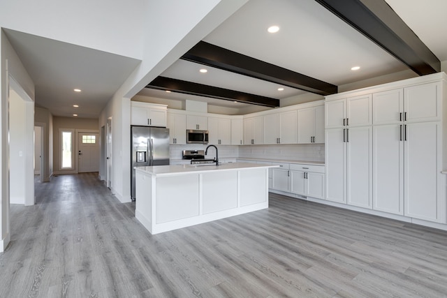 kitchen featuring beam ceiling, light hardwood / wood-style flooring, stainless steel appliances, and white cabinetry