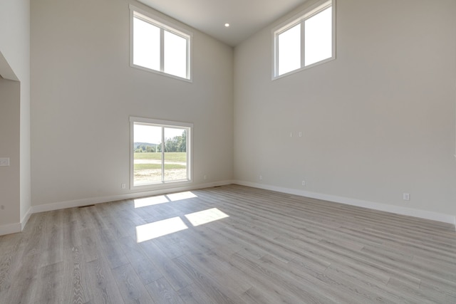 empty room featuring light wood-type flooring and a towering ceiling