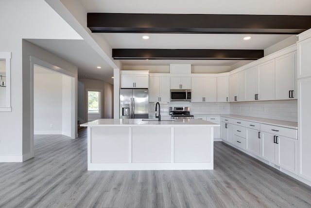 kitchen featuring beam ceiling, white cabinets, stainless steel appliances, and light hardwood / wood-style floors