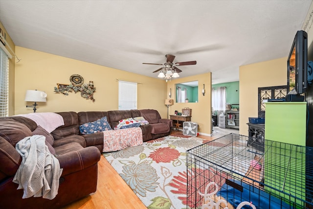 living room with a textured ceiling, ceiling fan, and hardwood / wood-style floors