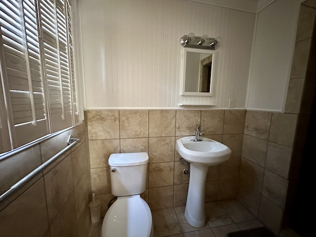 bathroom with toilet, tile walls, and tile patterned flooring