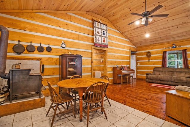 dining room featuring a wood stove, light hardwood / wood-style flooring, ceiling fan, and wooden ceiling