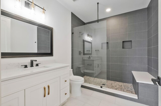 bathroom featuring toilet, a tile shower, vanity, and tile patterned floors