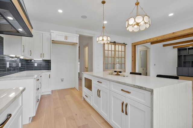 kitchen featuring backsplash, light hardwood / wood-style flooring, light stone counters, pendant lighting, and white cabinets