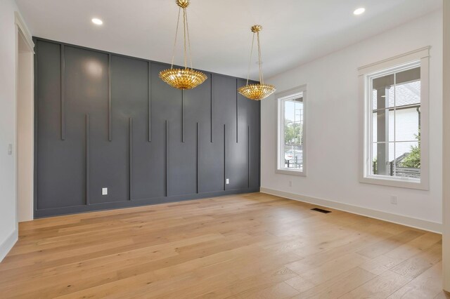 empty room featuring an inviting chandelier and light hardwood / wood-style floors