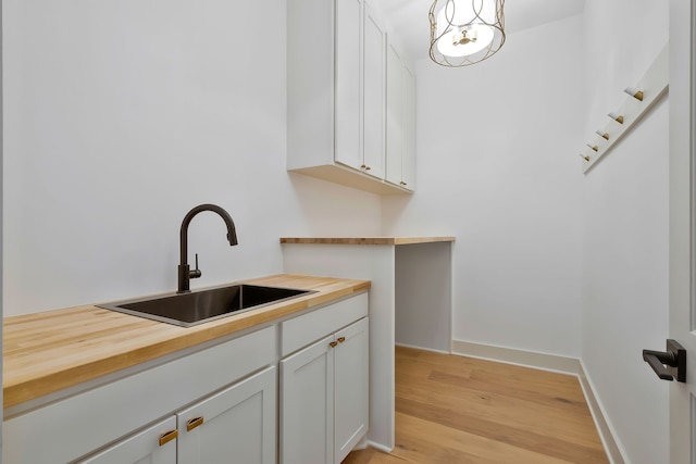 kitchen with sink, light hardwood / wood-style flooring, white cabinets, and wooden counters