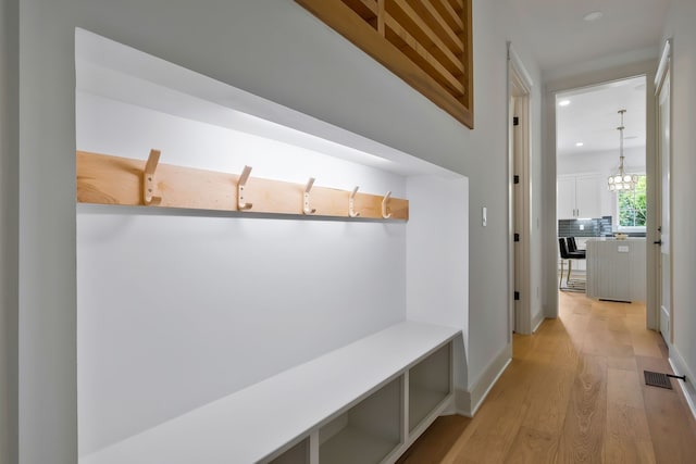 mudroom with light wood-type flooring and a chandelier