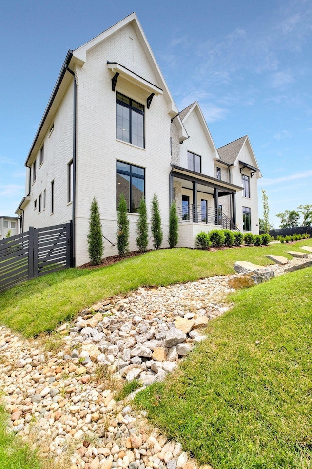 view of front of property featuring brick siding, fence, and a front yard