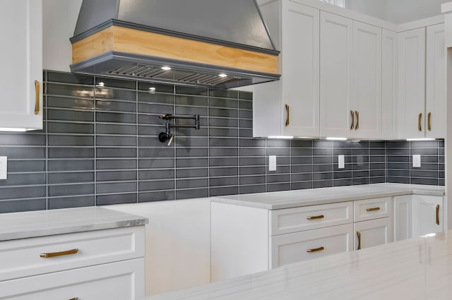 kitchen with white cabinetry, decorative backsplash, and light stone counters