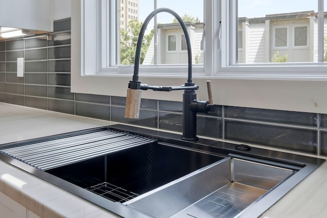 interior details featuring decorative backsplash, a sink, and white cabinets